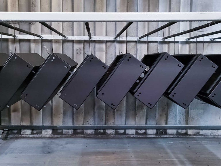 Lots of metal cabinets hung to dry in workshop after being powder coated black.